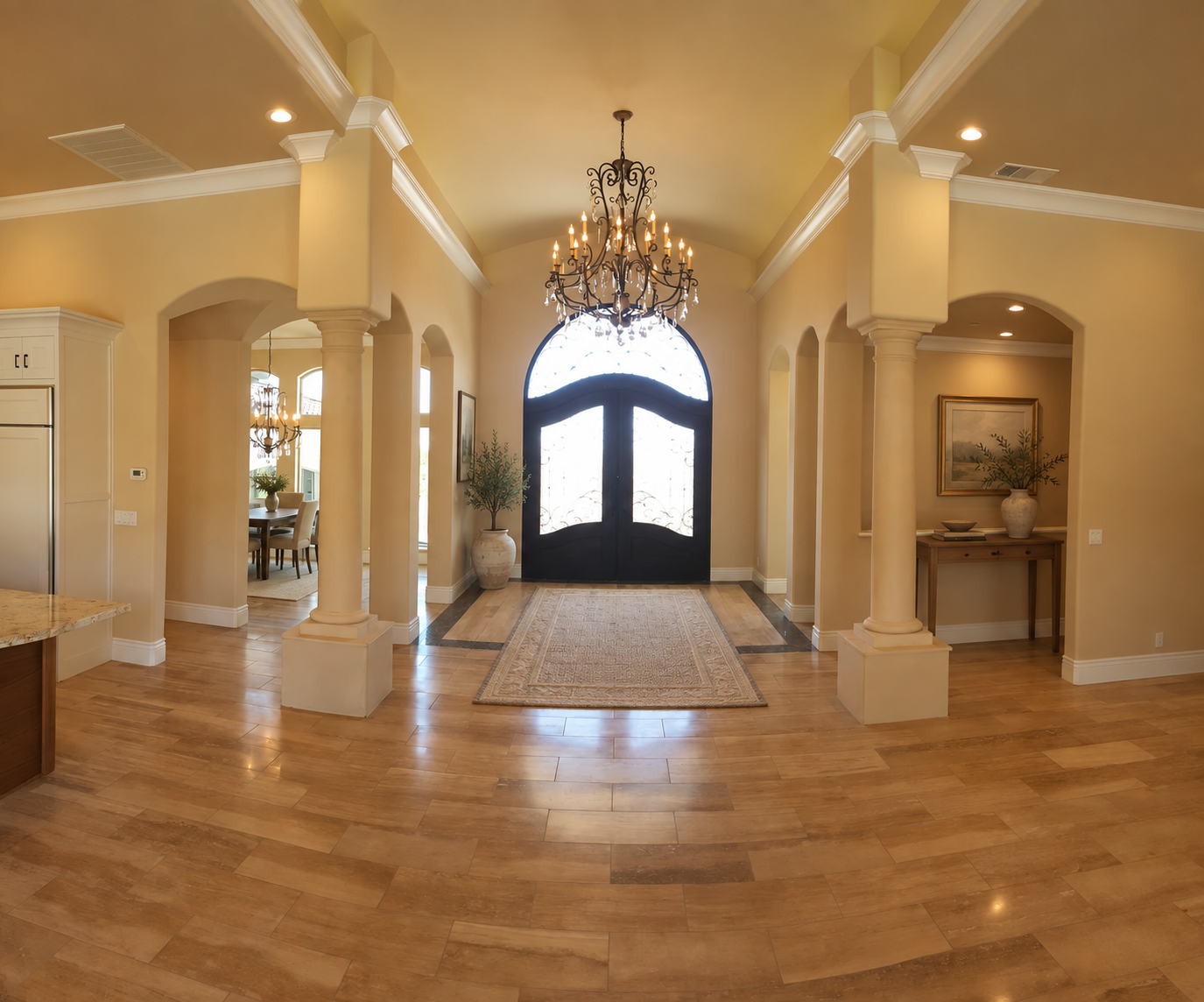 Entry hall with a chandelier, columns and warm stone flooring