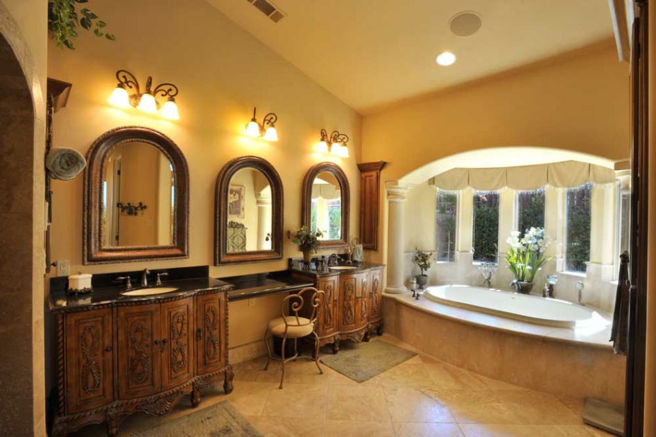 Primary bathroom with detailed wood vanities and a window-side tub
